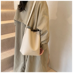 Chic cream bucket bag with lychee texture and gold-stamped lettering on a model