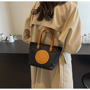 Detalle del bolso tote de nailon negro con correas de cuero y bordado en ambiente casual