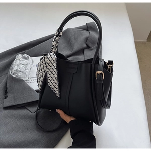 Detail of matte black bucket bag with geometric scarf and adjustable metal buckle