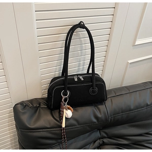 Detail of black baguette bag with white contrast stitching and baseball charm
