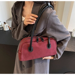 Detail of burgundy suede baguette bag with white contrast stitching and dual zippers