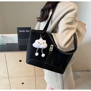 Large black textured tote bag with cute cloud charm shown on shoulder in lifestyle setting