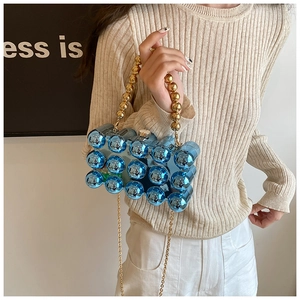 Detail view of bright blue acrylic evening clutch with gold bead handle and chain