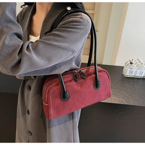 Detail of dark red suede baguette bag featuring white contrast stitching and slim black handle
