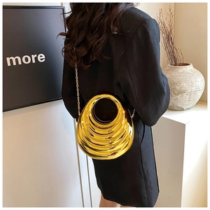 Detail of high-gloss gold acrylic clutch featuring layered waves and metal chain strap