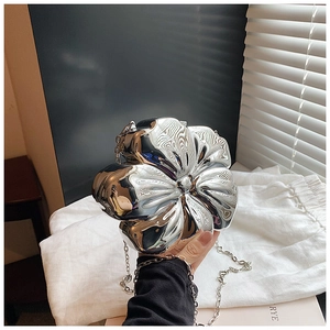 Detailed view of a silver mirror-finish flower-shaped evening bag with a metal chain strap