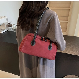 Detail of burgundy suede baguette bag with white contrast stitching and black handle