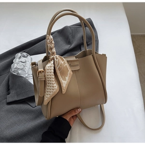 Detail of beige tote bag with decorative scarf and elegant office scene background