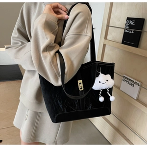 Detail of black tote bag with pleated texture, gold buckle and white cloud charm
