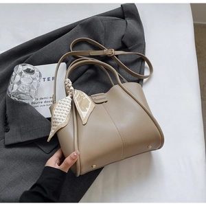 Close-up of light brown bucket bag with decorative scarf and gold hardware accents
