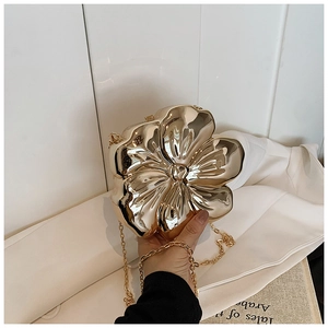 Detail of elegant gold flower clutch bag with mirror finish and detachable chain