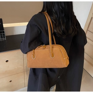 Detailed side view of caramel suede bowling bag with white stitching and zipper