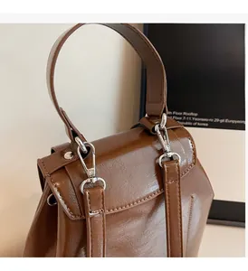 Detailed close-up of glossy brown leather backpack handle and silver metallic hardware