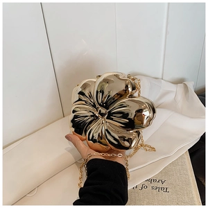 Close-up of elegant gold flower clutch bag with mirror-finish and metallic chain strap
