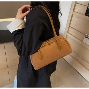 Detailed close-up of camel suede baguette bag with contrast white stitching and metal zipper