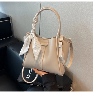 Detail view of cream PU bucket bag with magnetic closure and decorative silk scarf