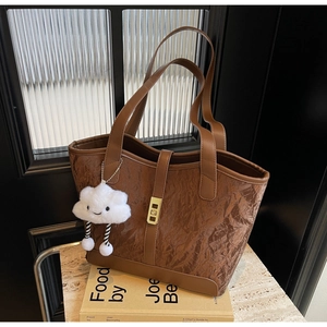 Deep brown textured tote bag with golden lock and cute white cloud pendant on books