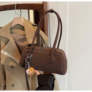 Macro shot of brown suede Boston bag with white stitching and baseball charm detail