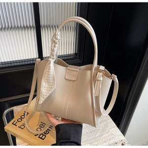 Detail of cream beige leather tote bag with decorative silk scarf and adjustable strap