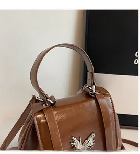 Detailed view of brown oil leather backpack featuring a silver butterfly buckle and sturdy handle