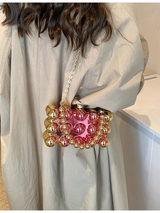 Modern acrylic evening bag with metallic red and gold spheres shown on a model