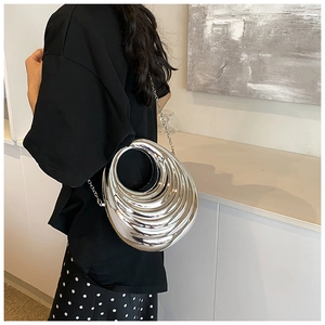 Silver metallic hard-shell clutch with spiral texture shown on person for size reference