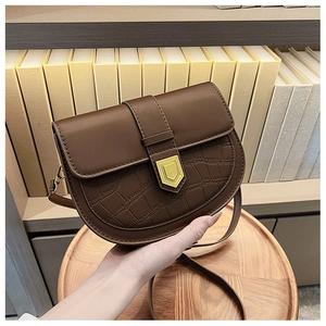 Detail of brown saddle bag with crocodile texture and gold hardware on vintage background