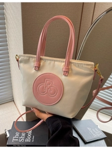 Bolso tote de nailon bicolor crema con correas de cuero rosa y detalles metálicos dorados