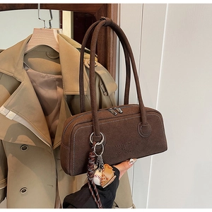 Detail of retro brown suede handbag featuring a unique baseball glove charm and zip closure