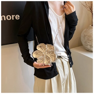 Silver metallic flower-shaped clutch bag with long chain strap worn by a model