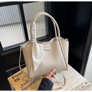 Detail of cream bucket bag with lychee texture and silk twilly scarf on handle