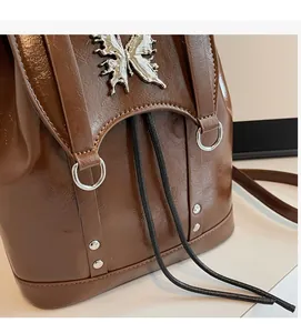 Detail of brown faux leather backpack featuring metallic butterfly and drawstring closure
