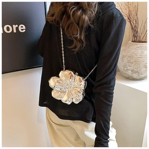 Macro view of silver floral evening bag with detailed metallic petals and chain strap