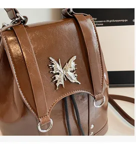 Close-up of vintage brown PU leather backpack with decorative silver butterfly buckle
