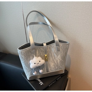 Detail of silver tote bag with pleated texture, gold buckle and cloud pendant accessory