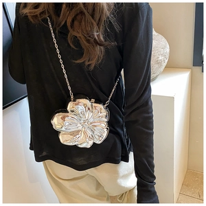 Detailed view of silver flower-shaped metallic evening clutch bag with fine chain strap