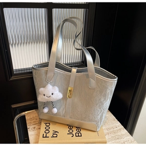 Close-up of silver wrinkled leather tote bag with gold buckle and plush cloud charm