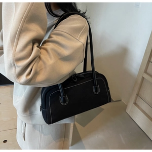 Detail of vintage black baguette bag with white contrast stitching and long handles