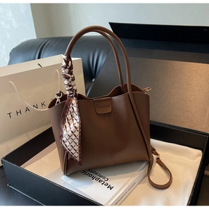 Detail of dark brown lychee leather tote with decorative scarf and buckle in gift box