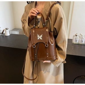 Close-up of brown faux leather backpack featuring a silver butterfly metallic buckle
