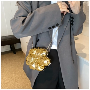 Detailed shot of a gold floral metal clutch with a sleek chain on a grey blazer
