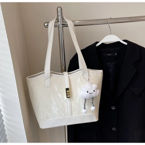 Detailed view of cream tote bag with crinkled patent texture and plush cloud charm