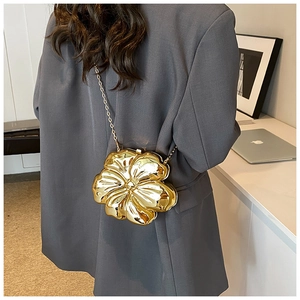 Detailed back view of a golden flower-shaped clutch bag worn over a grey blazer jacket