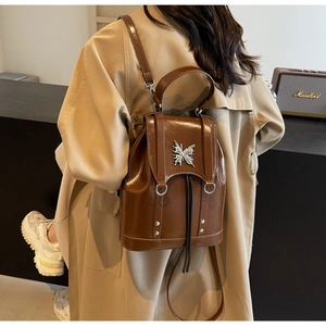 Detail of a dark brown vintage backpack with a silver butterfly buckle and stud accents