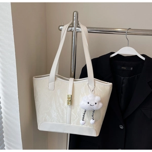 Close-up of pleated cream tote bag featuring a gold buckle and a fluffy cloud charm