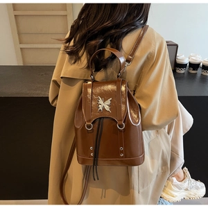Detail of brown patent leather backpack with silver butterfly ornament and drawstring