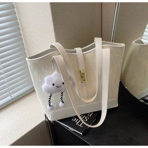 Detail of white textured leather tote bag with gold twist lock and plush cloud charm