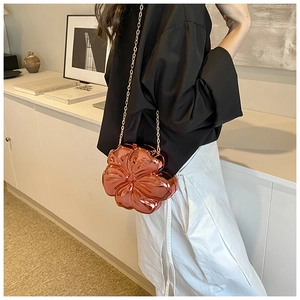 Rose gold flower-shaped metal clutch bag with gold chain strap on female model