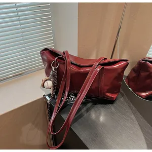 Detail of burgundy glossy leather tote bag with a decorative baseball themed keychain