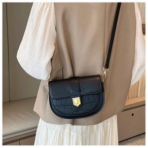 Detail of black saddle bag with crocodile embossing and gold buckle on a model